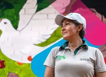 Retrato de mujer con gorra de béisbol con mural de una paloma de la paz al fondo