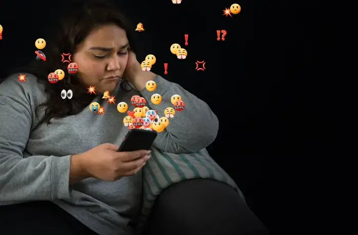 A woman looks at her phone concerned. AI powered abuse is threatening women and girls everywhere. There is no excuse for online abuse. Photo: UN Women