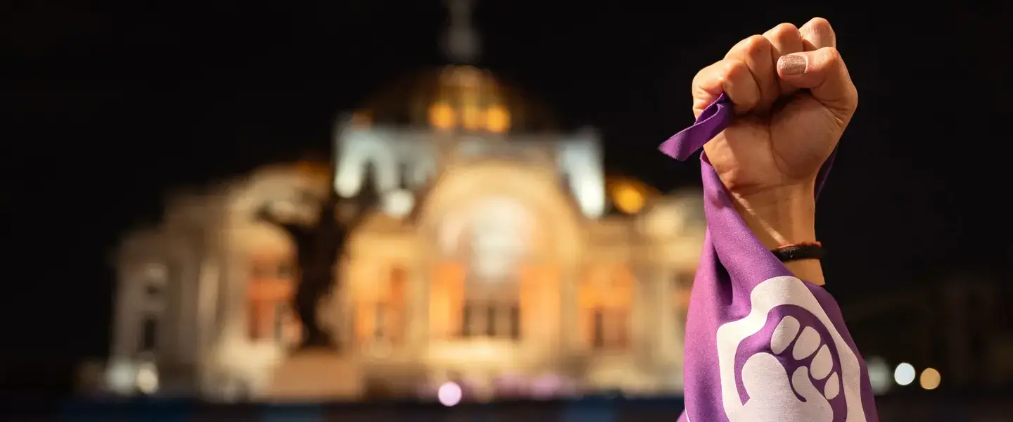 Un poing levé et un foulard violet du mouvement des femmes