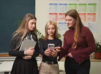 Three young women look at a phone