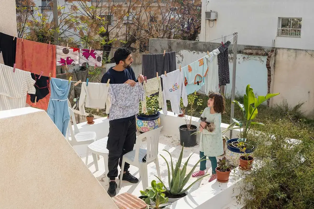 Un padre y su hija reparten juntos la colada, Túnez. 2023. Foto: ONU Mujeres/Séverine Sajous.
